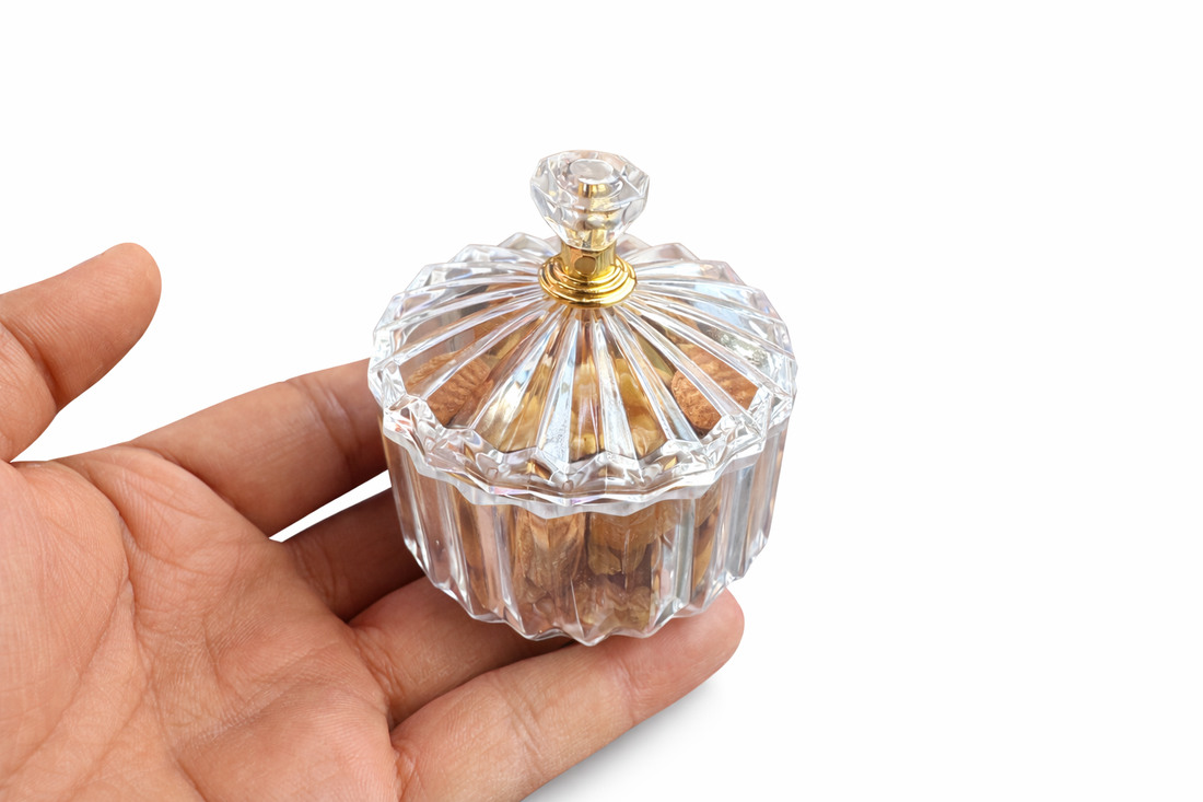 Hand holding a glass container filled with nuts on a decorative background with lights and flowers.